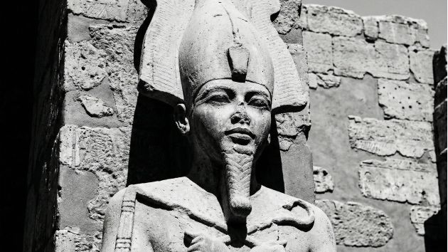 Escultura em pedra de uma divindade antiga representando força e potência masculina.