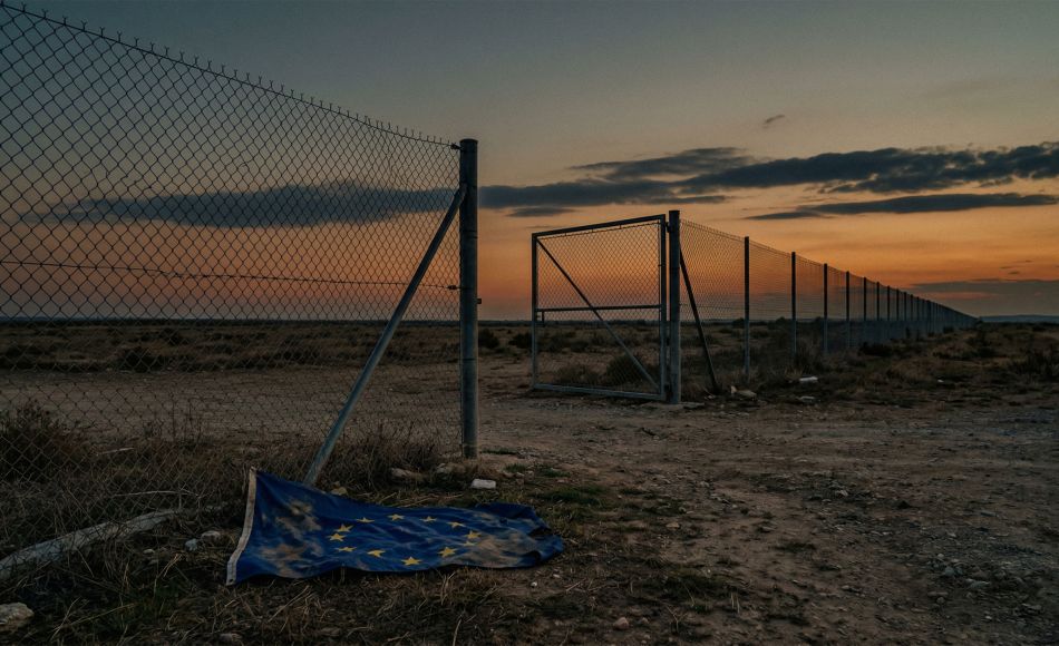 A wire border fence stretches across an open landscape at dusk, with the gate standing open and no enforcement presence visible — a visual metaphor for Europe's immigration enforcement gap.