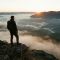 A man overlooks a rugged mountain landscape during a solo expedition.
