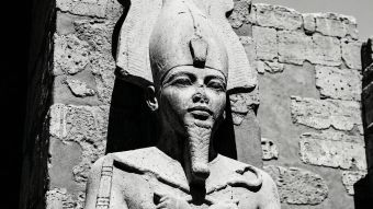 Escultura em pedra de uma divindade antiga representando força e potência masculina.