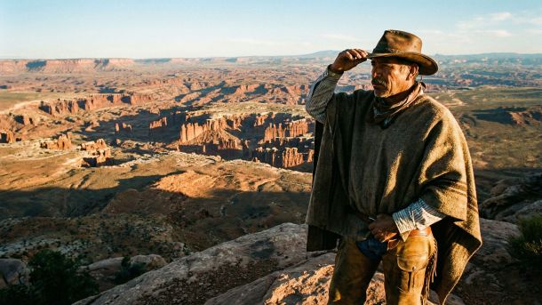 Un hombre fuerte observando una cordillera que representa la virilidad masculina tradicional y el rol de proveedor.