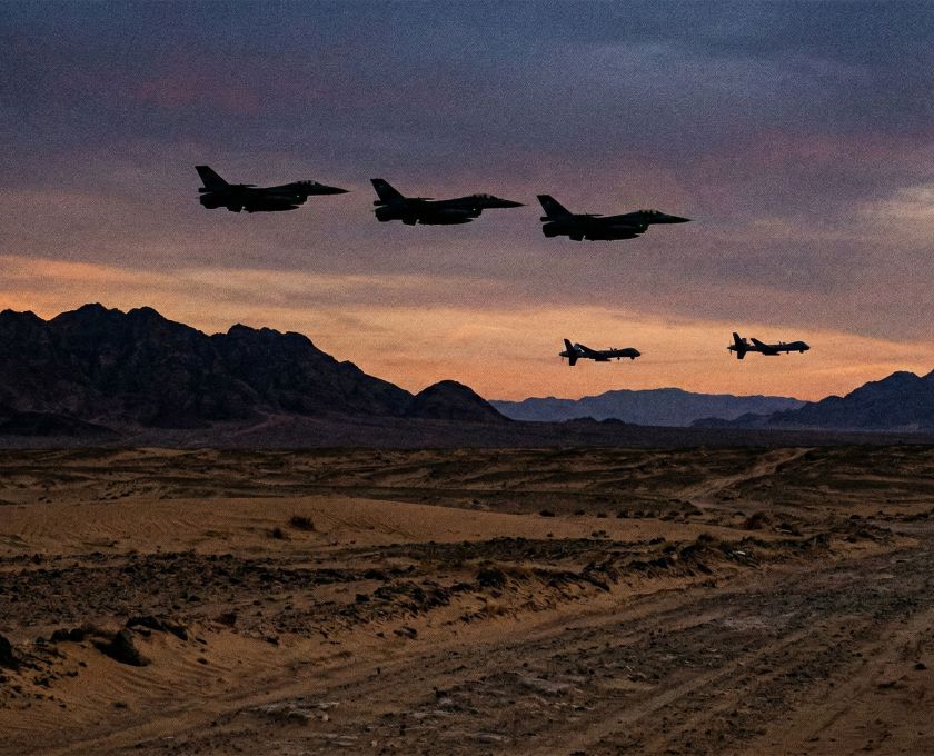 Military aircraft flying over a desert landscape during a strategic operation.