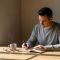 Hombre reflexionando y escribiendo en cuaderno mientras diseña un estilo de vida alineado con sus valores.